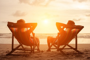 Couple laying on beach chairs looking at sunset